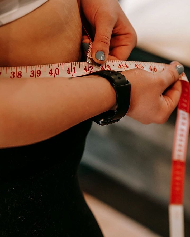 Mulher medindo a cintura com fita métrica